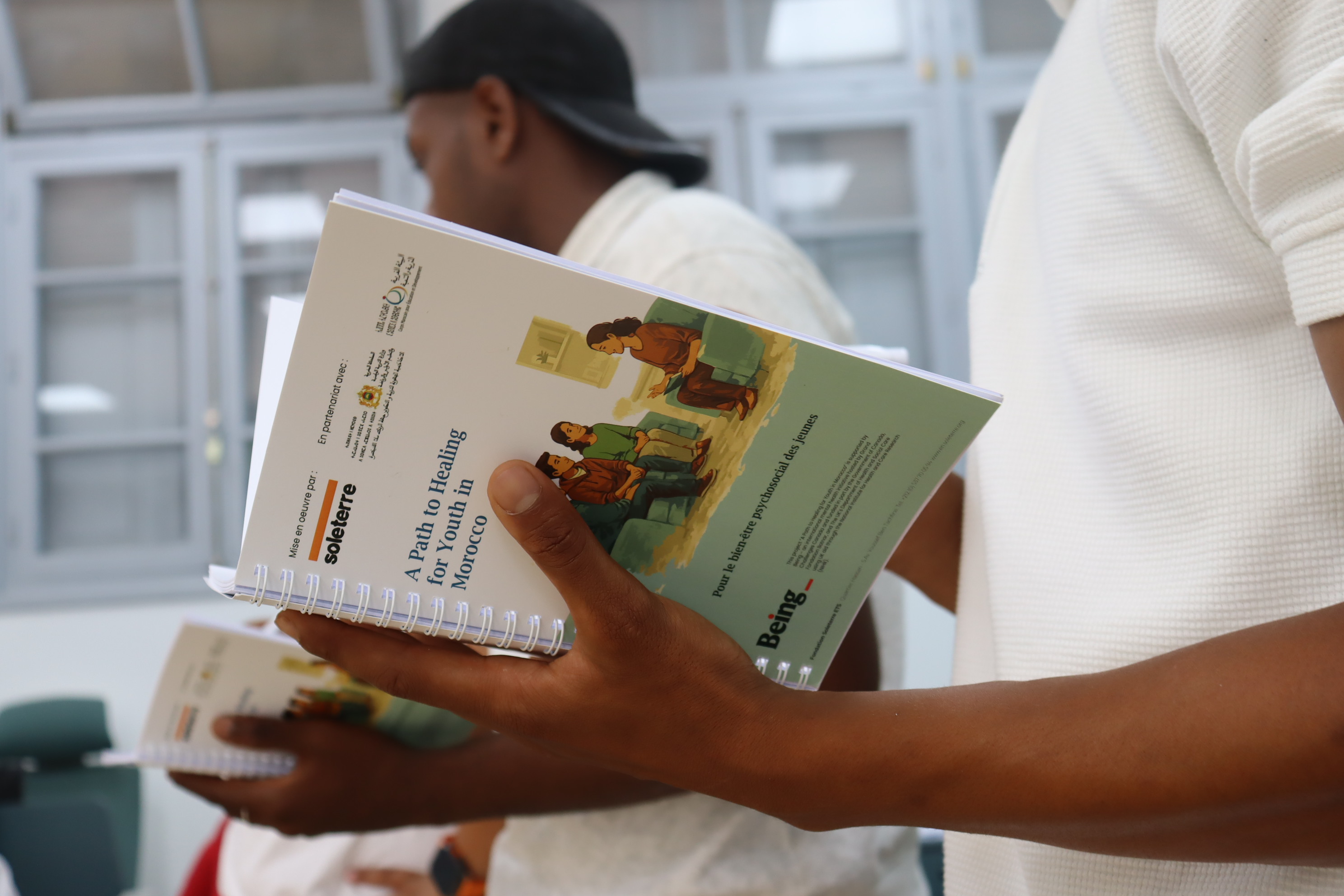 Guide A Path to Healing for Youth in Morocco du programme Being de Soleterre, tenu en main lors d un atelier sur le bien-etre psychosocial des jeunes